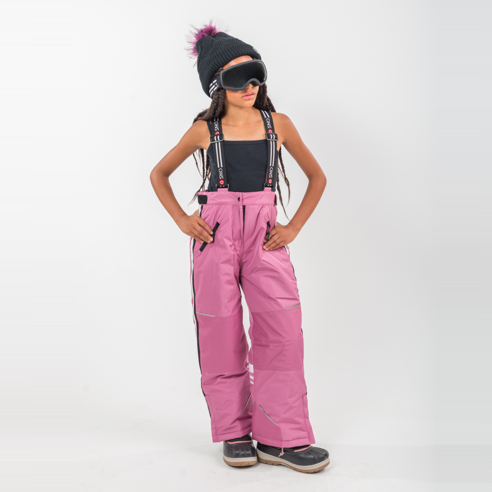 Person wearing pink snow pants and a black beanie with a pom-pom on a white background
