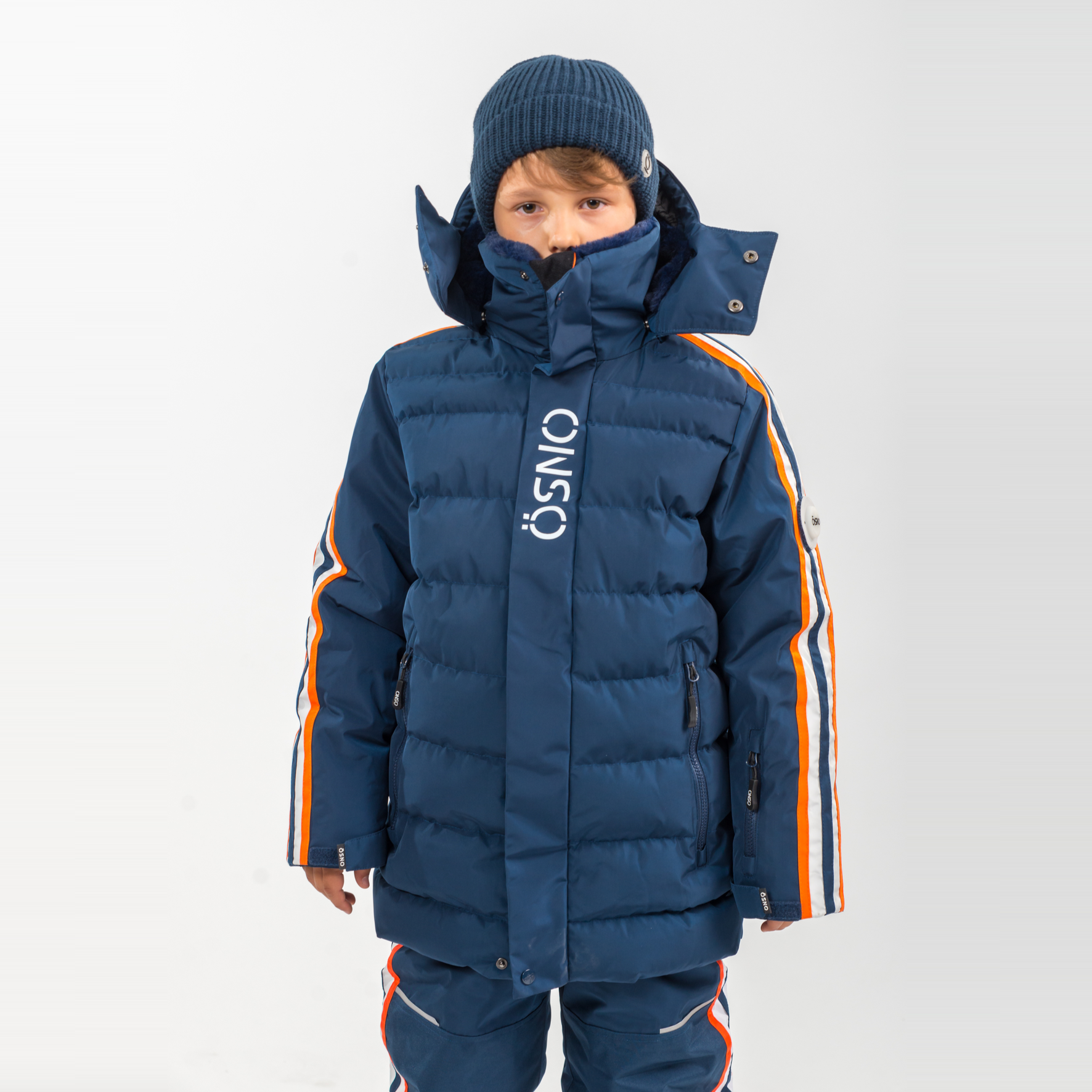 Child wearing a blue winter coat with orange accents on a white background